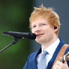 Ed Sheeran grający na gitarze i śpiewający do mikrofonu.